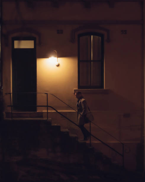 istock Gentleman in overcoat ascending steps at night 1324337040