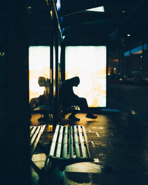 Silhouette of a man sitting with head nodded at bus stop terminal