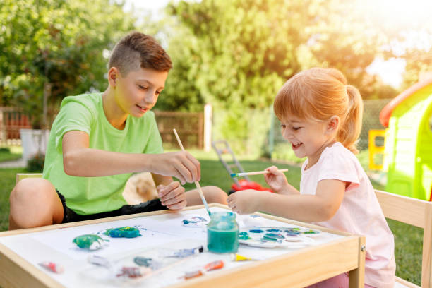 Cheerful siblings using watercolors outdoors