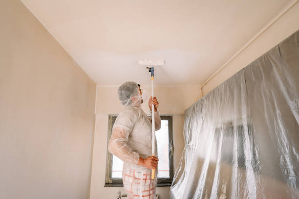 istock Man In Protective Workwear And Mask Working With Paint Roller On Wall In Kitchen At Home 1324341085