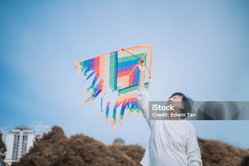 asian chinese senior woman playing kite in public park during sunny day morning Kite - Toy Stock Photo