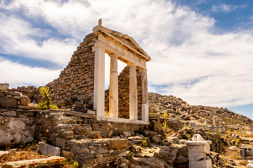 Well preserved Temple of Isis side view on Delos Island located on the hill above the ancient city with blue sky and clouds in the background, Greece.