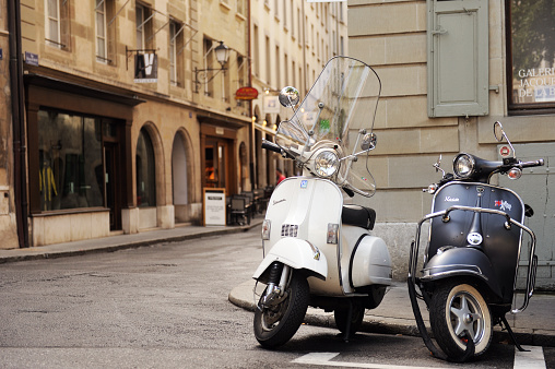 Geneva, Switzerland  - 07.18.2015: Two VESPA scooters in retro style are standing next to a parking lot in an empty city.