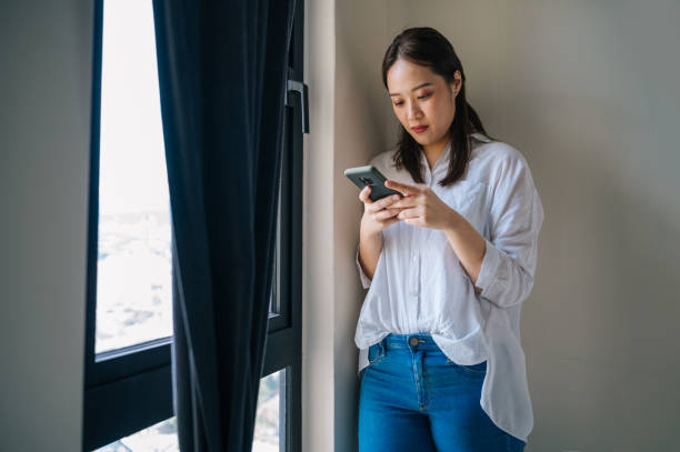 istock Beautiful young Asian woman using smartphone and smiling 1324343559