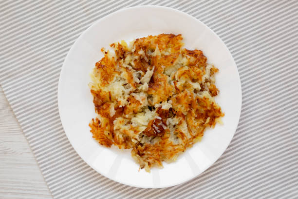 hashbrowns frits faits maison sur une assiette blanche, vue de dessus. pose plate, au-dessus, d’en haut. - hash brown gold food vegetable photos et images de collection