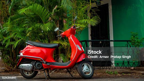 Red Scooter Parked Against Green Background At The Street Stock Photo - Download Image Now