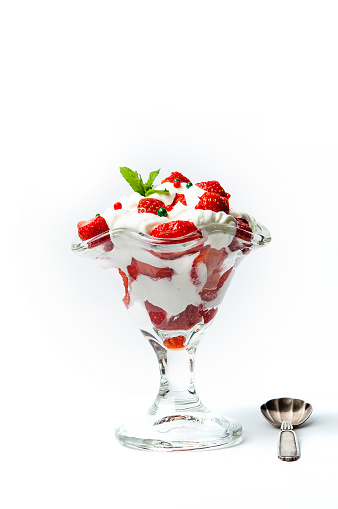 Strawberry and whipped cream summer dessert in a glass cup for a refreshing sweet snack isolated on white background