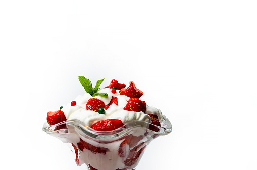 Strawberry and whipped cream summer dessert in a glass cup for a refreshing sweet snack isolated on white background