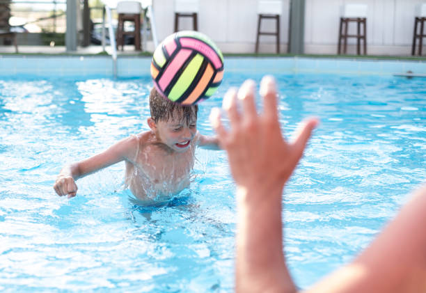 istock Boy kicking a ball with head into pool 1324345962