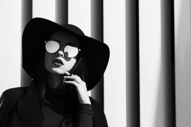 트렌디한 모자와 셔터에서 포즈를 취하는 스타일리시한 안경을 착용한 모델의 패션 초상화. 블랙 앤 화이트 토닝 - 4407 뉴스 사진 이미지