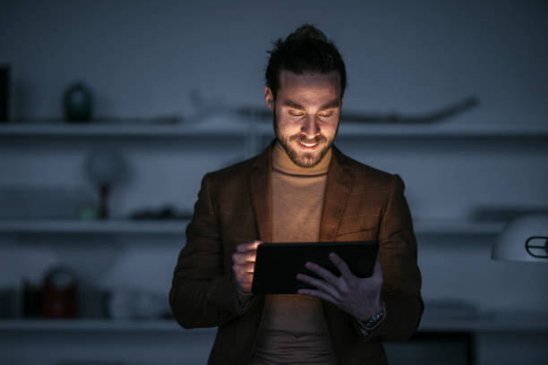 istock Late Night Work At Home: Smiling Businessman With Beard Using Tablet 1324348215