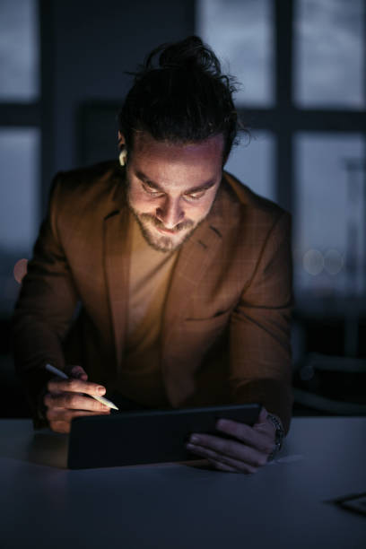 istock Late Night Work At Home: Smiling Businessman With Beard Looking At Tablet 1324348233