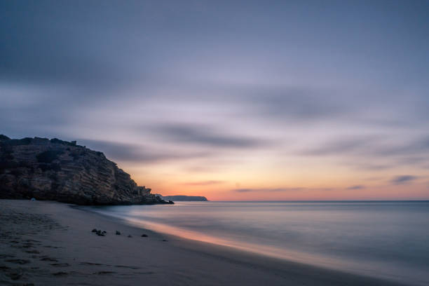 ciel coloré le matin avec du rocher avant le lever du soleil à praia da figueira, portugal - long exposure rock cloud sky photos et images de collection