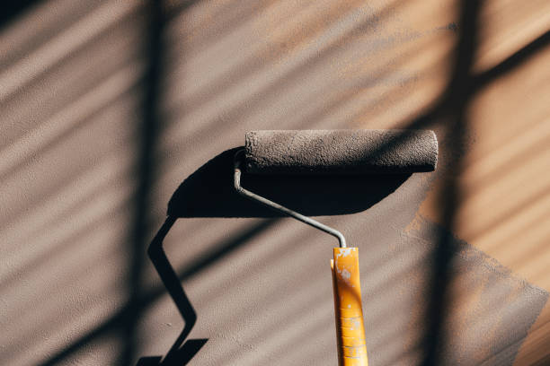 Painting wall in light brown color with paint roller