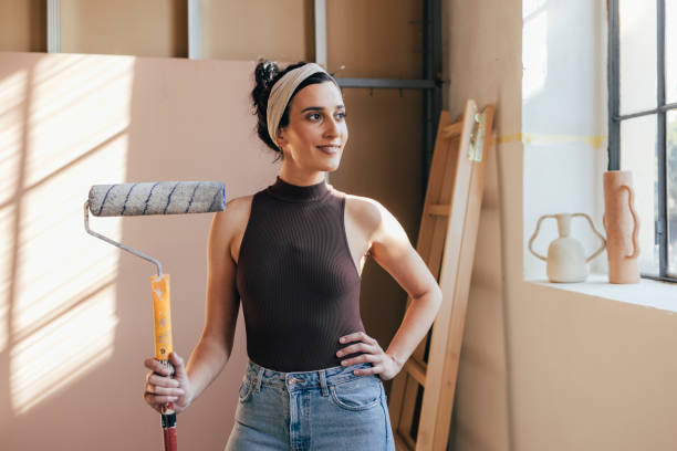 istock Smiling Woman Posing With Paint Roller 1324350594