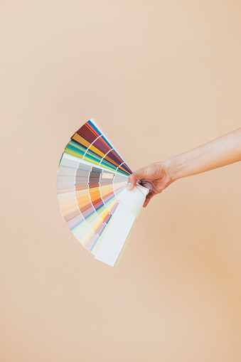 Woman choosing color swatch of the wall at home