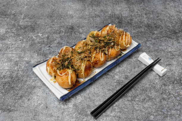 Japanese food Takoyaki or octopus balls topped with dried fish and seaweed on the grey concrete table. Japanese food Takoyaki or octopus balls topped with dried fish and seaweed on the grey concrete table. takoyaki photos stock pictures, royalty-free photos & images