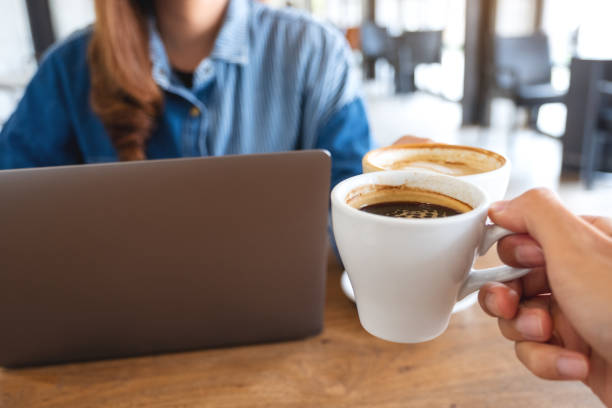 istock a woman and a man clinking coffee cups together while working on laptop computer 1324351659