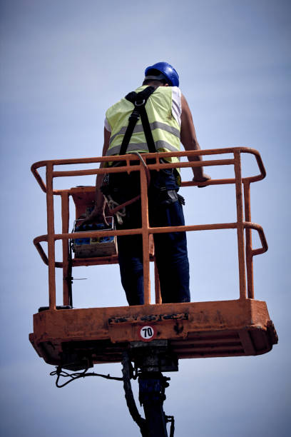 istock Manual worker on a telescopic lifter basket fixing street light pole. 1324355518