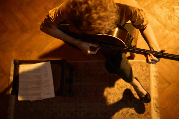 woman playing acoustic guitar in a retro vintage room. - fingerstyle imagens e fotografias de stock