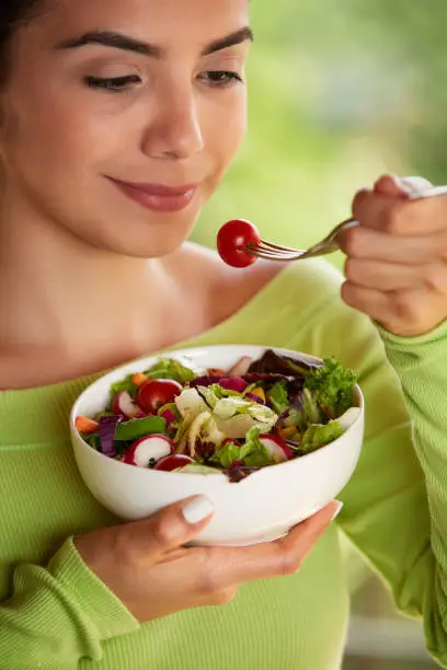 Close-up of a Hispanic cute young woman eating vegan salad at lunch