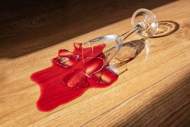 vidrio roto con vino tinto filtrado en el suelo de madera de la casa. el abuso del alcohol, la imagen conceptual. - glass broken spilling drink fotografías e imágenes de stock