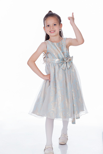 Beautiful Latina girl from Bogota Colombia between 4 and 5 years old, points to the sky with her finger while wearing her ceremony dress and smiles in a beautiful portrait