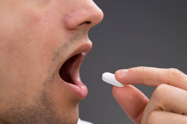 istock Man Taking Medicine Against Gray Background 1324370836