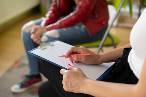 Close up of a psychologist notes and a students knees Close up of a therapists notes and a students knees during a mental health meeting in a stylish office photos of anorexia pictures stock pictures, royalty-free photos & images