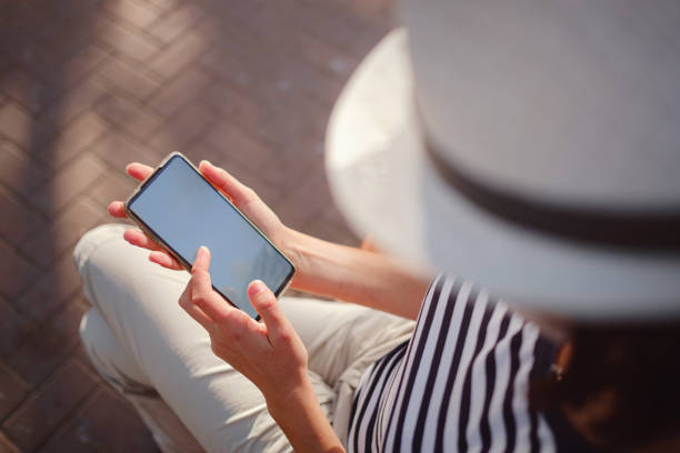 istock A woman wearing a protective mask looks at her smartphone display 1324378805