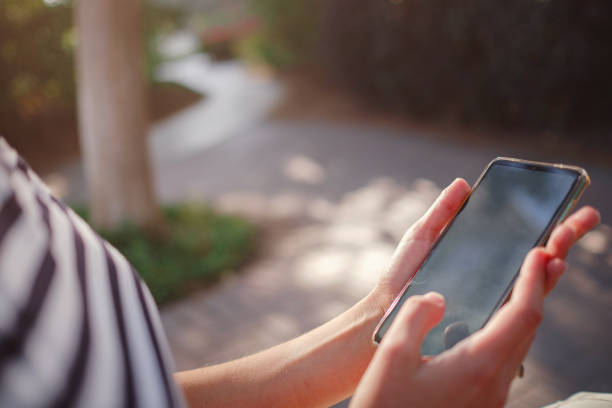 istock A woman wearing a protective mask looks at her smartphone display 1324378832