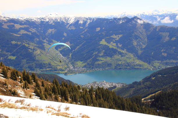 parapente vuela desde el schmittenhöhe hacia el lago zell - paragliding sport austria parachuting fotografías e imágenes de stock