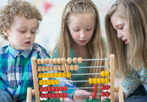 Kids gather around and use an abacus together.