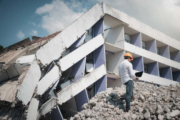 Engineer holding laptop is checking for destruction, demolishing building. stock photo