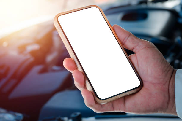 un homme debout devant une voiture avec un capot donnant sur la salle des machines et utilise le téléphone pour contacter le centre de réparation automobile via l’application smartphone - automotive repair center photos et images de collection