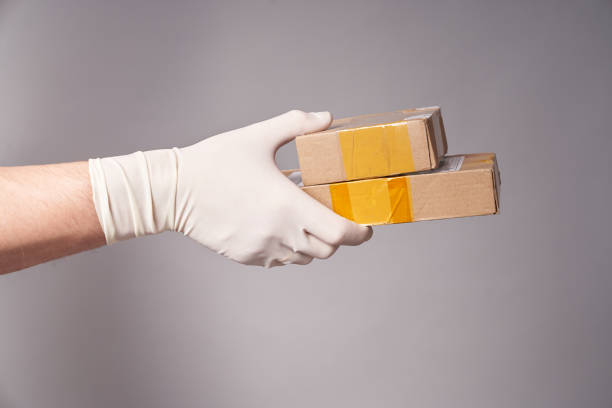 istock Hand of a man in a glove with two parcels on a gray background 1324394105