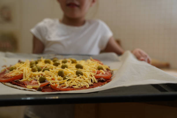 a garota segura uma assadeira preparada para assar pizza com carne. cozimento. - bread food baked 7 grain bread - fotografias e filmes do acervo