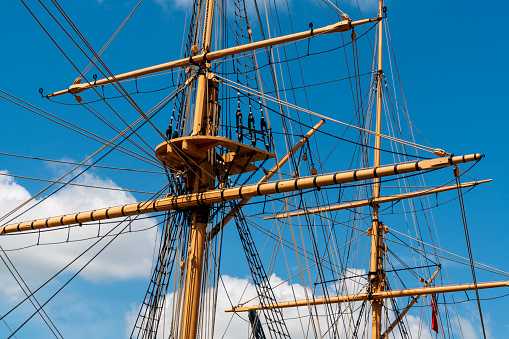 Gleaming in the sun, the mast, platform, stays and spars of an old sailing ship.