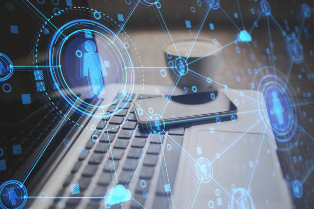 istock Close up of desktop with laptop and creative glowing blue business interface on blurry background. Human resources and online recruitment concept. Double exposure. 1324400386