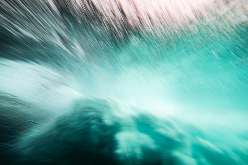 Motion blur of under a breaking blue ocean wave