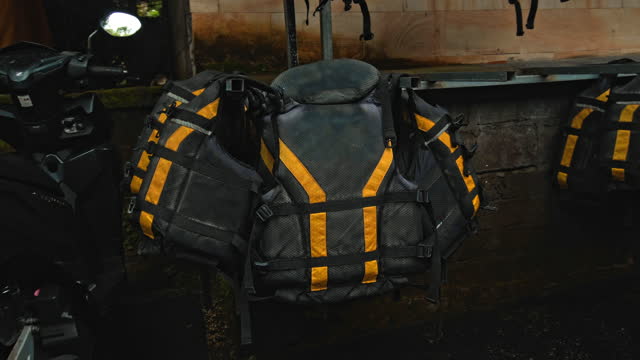 Black protective jackets with yellow lines and protective helmets to practice rafting hanging on a wall