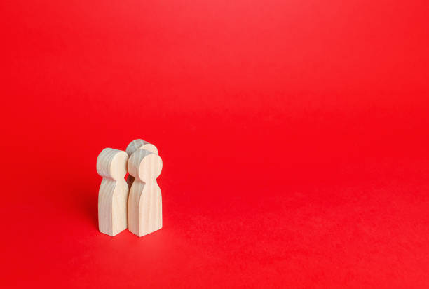 istock Three human figurines on a red background. Communication and discussion. Friendly relations. A meeting. Assistance, cooperation and collaboration. Place for text. 1324410429