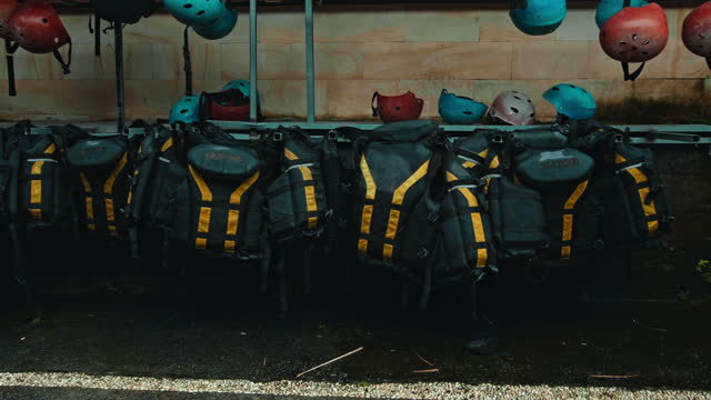 Black protective jackets with yellow lines and protective helmets to practice rafting hanging on a wall