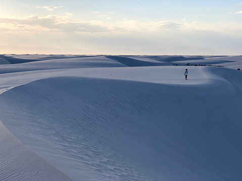 White Sands NP, New Mexico, USA - May 31, 2021: Female tourist is standing on sand dune in White Sands National Park in New Mexico, USA.