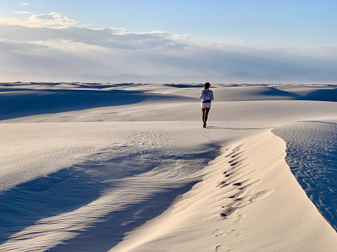 White Sands NP, New Mexico, USA - May 31, 2021: Female tourist is walking on sand dune in White Sands National Park in New Mexico, USA.