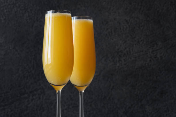 Buck's Fizz cocktails Two glasses of Buck's Fizz cocktail on black background mimosa stock pictures, royalty-free photos & images