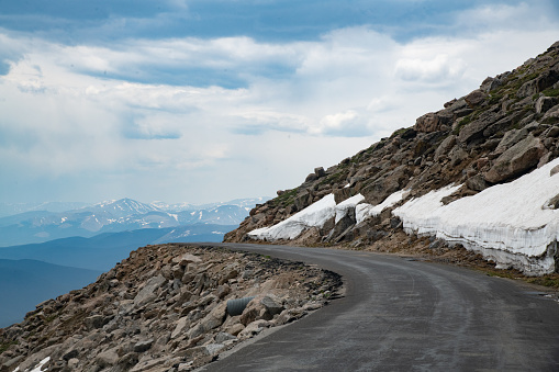 A view ahead on the highest paved road in the United States (USA) with 14000 feet mountains in the background. This is on Mount Evans which in a National Forest near Idaho Springs, Colorado west of Denver, Colorado in western USA.  John Morrison - Photographer