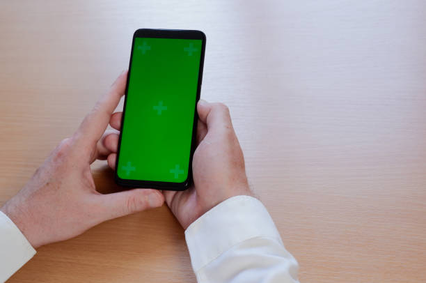istock Man's hand using mobile smartphone with green screen. Mock up mobile 1324419634