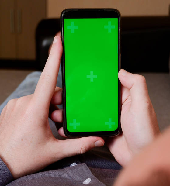 istock A young man in a gray shirt lying on a sofa and using a smartphone with a vertical green screen 1324419647