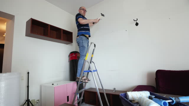 Funny middle aged man is trying to fix the shelf